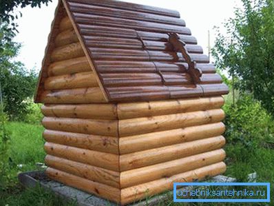 La maison et le puits à l'intérieur. La combinaison de métal (toit de carton ondulé) et de bois (murs de rondins arrondis) La maison et le puits à l'intérieur. La combinaison de métal (toit de carton ondulé) et de bois (murs de rondins arrondis)