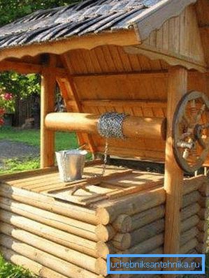 Sur la photo - un puits avec une trappe sous un auvent